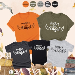 Op de afbeelding: Set van vijf t-shirts in verschillende kleuren met de tekst "broer van een engel", "moeder van een engel" en "vader van een engel" erop gedrukt.