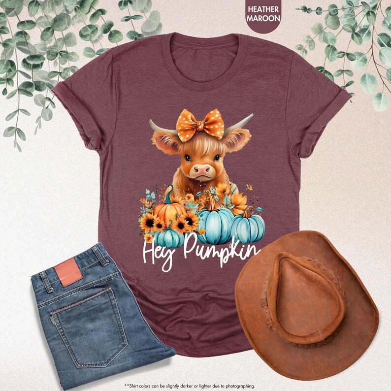 a t - shirt with a picture of a cow wearing a bow and pumpkins