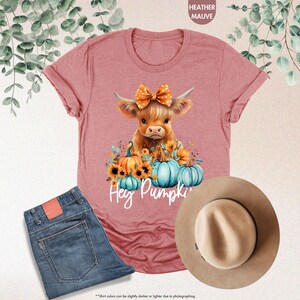 a pink shirt with a cow wearing a bow and pumpkins