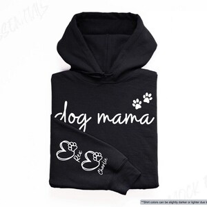 May include: Black hoodie with the words "dog mama" in white script, along with paw prints and the names "Rex" and "Charlie." The hoodie has a drawstring hood and a kangaroo pocket.