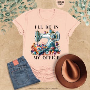 K&ouml;nnte beinhalten: Ein pinkfarbenes T-Shirt mit einer N&auml;hmaschinengrafik und dem Text "Ich bin in meinem B&uuml;ro".