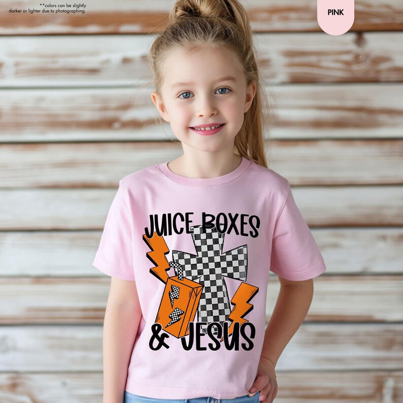 a little girl wearing a pink shirt with a cross on it