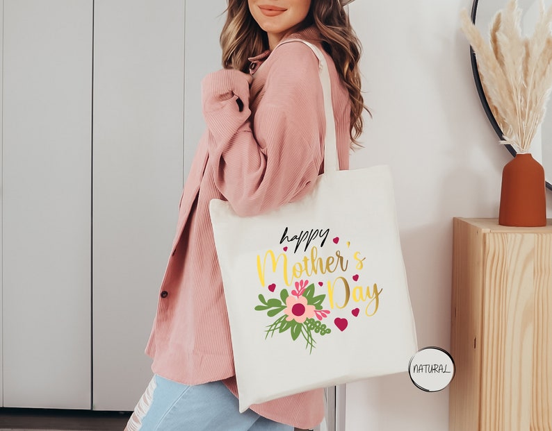 a woman holding a white tote bag that says happy mother's day