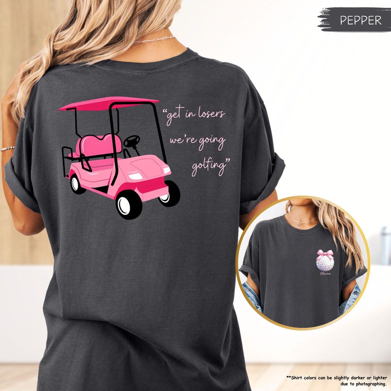 May include: Dark grey t-shirt with a pink golf cart graphic and the text "get in losers we're going golfing". The shirt also has a small graphic of a golf ball with a pink bow.