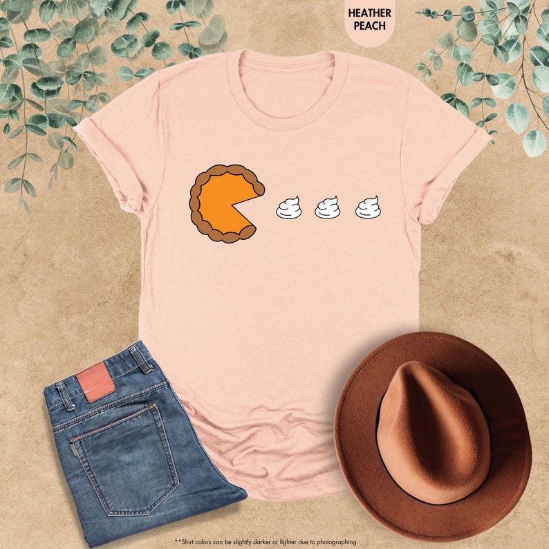 May include: A pink t-shirt with a graphic of a pumpkin pie with a slice missing and three dollops of whipped cream. The text "HEATHER PEACH" is at the top of the image.