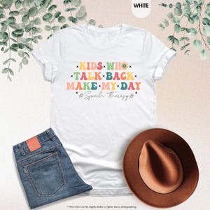 May include: White t-shirt with a colorful graphic that says "KIDS WHO TALK BACK MAKE MY DAY #Speech therapy#"