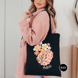 a woman holding a black tote bag with a picture of a brain