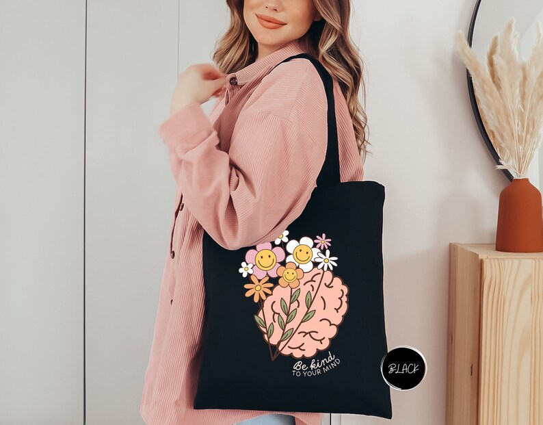 a woman holding a black tote bag with a picture of a brain