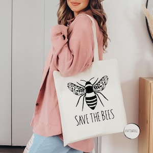 May include: A white tote bag with a black bee illustration and the text "Save the Bees".