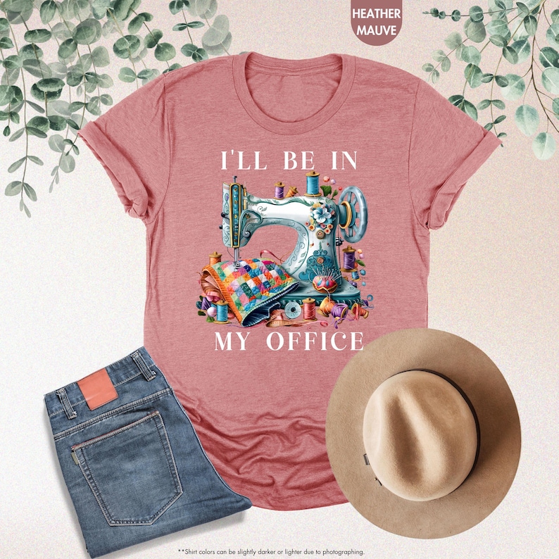 K&ouml;nnte beinhalten: Ein T-Shirt in der Farbe Heather Mauve mit einer wei&szlig;en Grafik einer N&auml;hmaschine und dem Text "I'll be in my office".