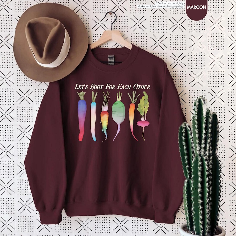 May include: Maroon sweatshirt with the text "Let's Root For Each Other" and a watercolor illustration of colorful carrots and radishes.