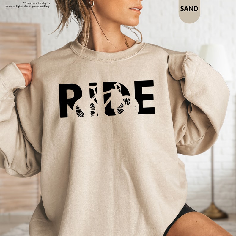 a woman wearing a sweatshirt with the word ride printed on it
