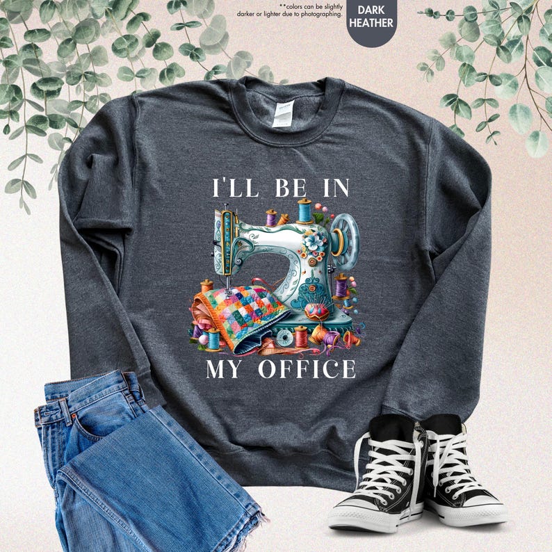 K&ouml;nnte beinhalten: Dunkelgrauer Sweatshirt mit einer bunten N&auml;hmaschine und dem Text "Ich bin in meinem B&uuml;ro".