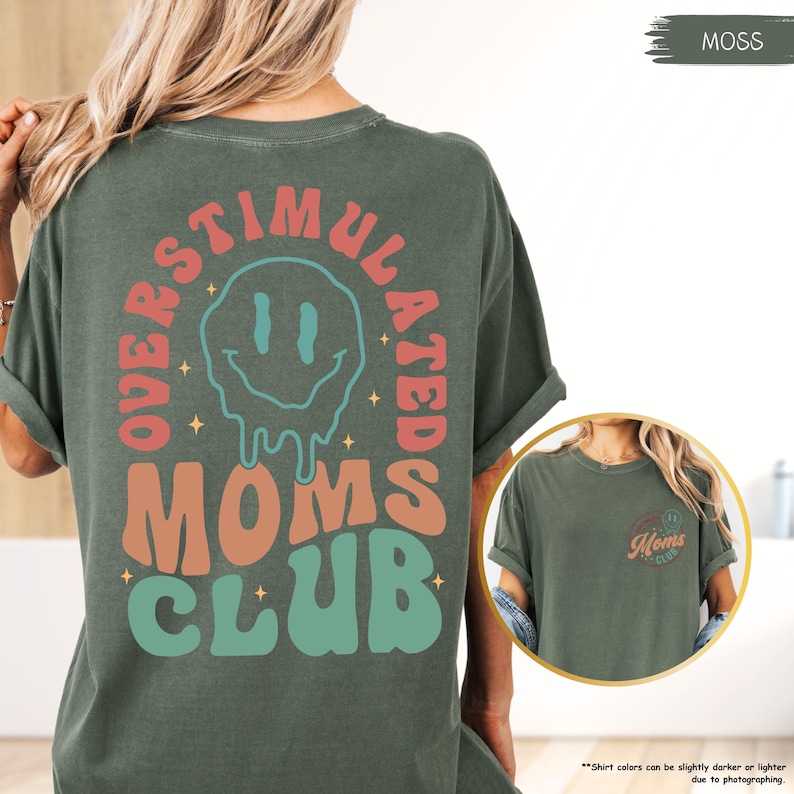 K&ouml;nnte beinhalten: Moosgr&uuml;nes T-Shirt mit dem Schriftzug "OVERSTIMULATED MOMS CLUB" in Retro-Schrift und einem schmelzenden Smiley-Gesicht. Das Shirt hat kurze &Auml;rmel und eine lockere Passform.