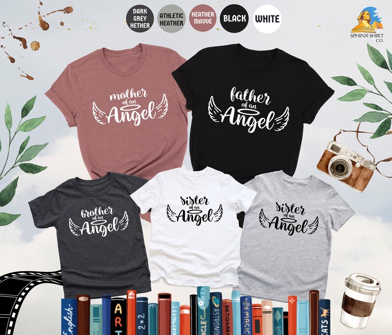 Op de afbeelding: Vijf T-shirts in verschillende kleuren en ontwerpen. De shirts hebben de tekst "moeder van een engel", "vader van een engel", "broer van een engel" en "zus van een engel" erop gedrukt. De shirts zijn in een rij gerangschikt, met het shirt "moeder van een engel" vooraan.