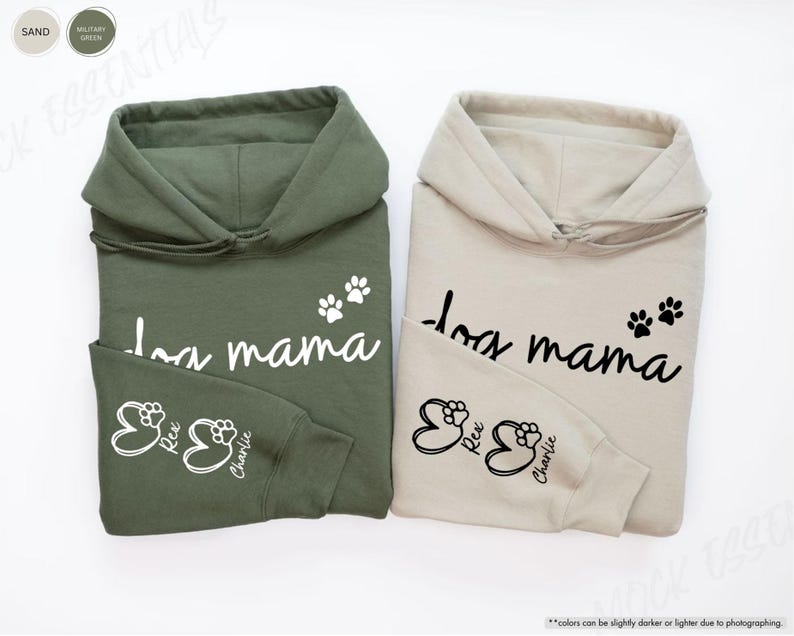 May include: Two hooded sweatshirts, one military green and one sand-colored, each featuring the text "dog mama" and paw prints. The sleeves display paw prints with the names "Rex" and "Charlie". The sweatshirts are made of a soft material.