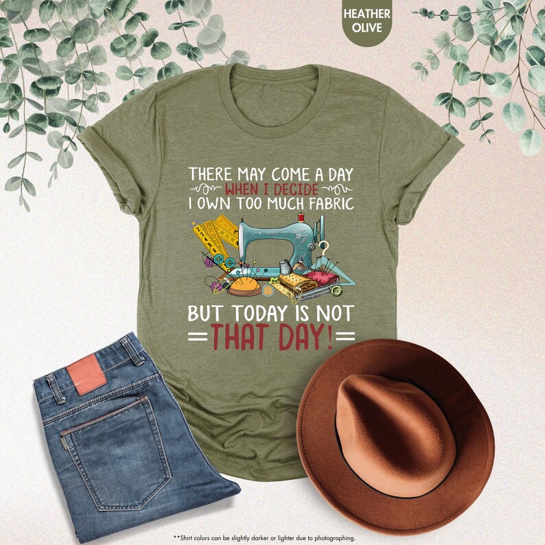 May include: A green t-shirt with a sewing machine and fabric design. The text on the shirt reads "There may come a day when I decide I own too much fabric but today is not that day!"