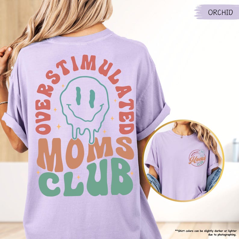 K&ouml;nnte beinhalten: Ein helllila T-Shirt mit dem Schriftzug "OVERSTIMULATED MOMS CLUB" in Retro-Schrift und einem schmelzenden Smiley-Gesicht. Das Shirt hat auch eine kleinere Grafik auf der Vorderseite. Das Shirt hat eine lockere Passform.