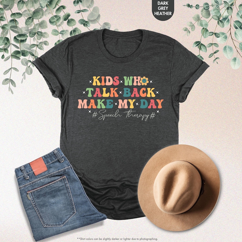 May include: Dark heather grey t-shirt with a rainbow design that says "KIDS WHO TALK BACK MAKE MY DAY #Speech Therapy#"