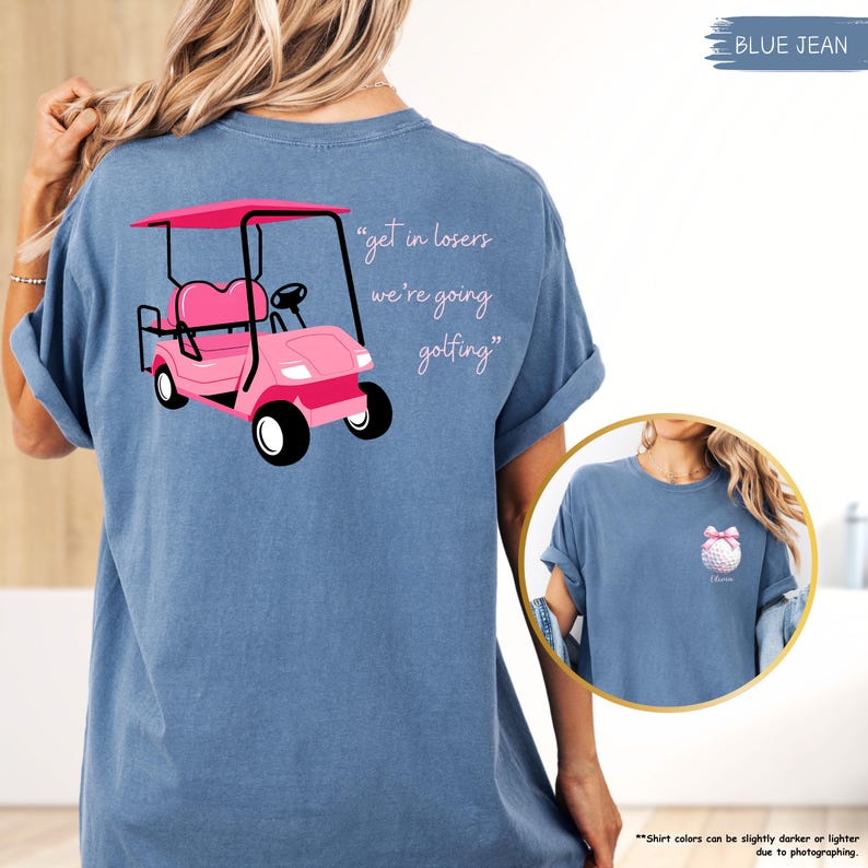 May include: Blue jean t-shirt with a pink golf cart graphic and the text "get in losers we're going golfing." The shirt also has a small golf ball graphic with a pink bow. The shirt is a comfortable, casual style.