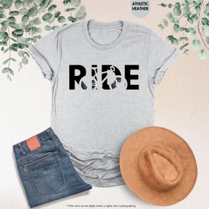 a t - shirt that says ride next to a hat and jeans