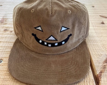 Tan Corduroy Trucker Hat with Jack-O’-Lantern Face – Embroidered Halloween Pumpkin Cap – Cozy Fall Western Hat – Spooky Season Accessory