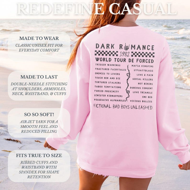 Puede incluir: Una sudadera rosa claro con el texto "DARK ROMANCE 1982 WORLD TOUR DE FORCED" en negro. La parte posterior de la sudadera presenta una lista de frases y palabras. La sudadera tiene pu&ntilde;os y cintura acanalados.