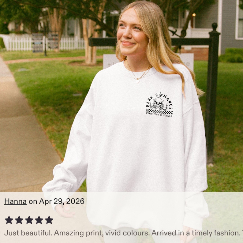 Puede incluir: Sudadera blanca con un gr&aacute;fico en blanco y negro en el pecho superior. El gr&aacute;fico incluye una calavera y el texto "DARK ROMANCE" y "WORLD TOUR DE FORCED". La sudadera es de manga larga.