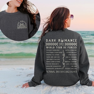 Puede incluir: Sudadera gris oscuro con un gr&aacute;fico en la parte delantera y trasera. El gr&aacute;fico frontal presenta una calavera y las palabras "Dark Romance World Tour De Forced". El gr&aacute;fico trasero enumera las fechas de la gira y los t&iacute;tulos de las canciones.