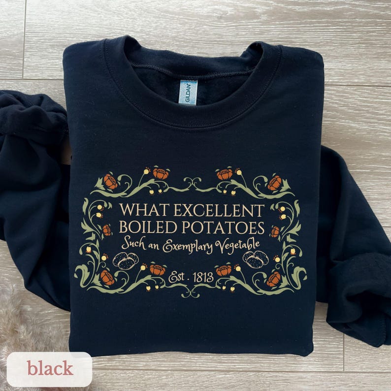 Puede incluir: Sudadera negra con un dise&ntilde;o decorativo y el texto "WHAT EXCELLENT BOILED POTATOES Such an Exemplary Vegetable Est. 1813". El dise&ntilde;o incluye elementos florales naranjas y verdes.