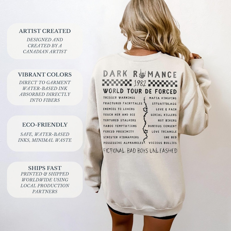 Puede incluir: Sudadera de color crema con el texto "DARK ROMANCE 1982 WORLD TOUR DE FORCED" en negro. La parte posterior de la sudadera presenta una lista de frases. La sudadera tambi&eacute;n tiene texto en el lado izquierdo que dice "ARTIST CREATED" y "VIBRANT COLORS".