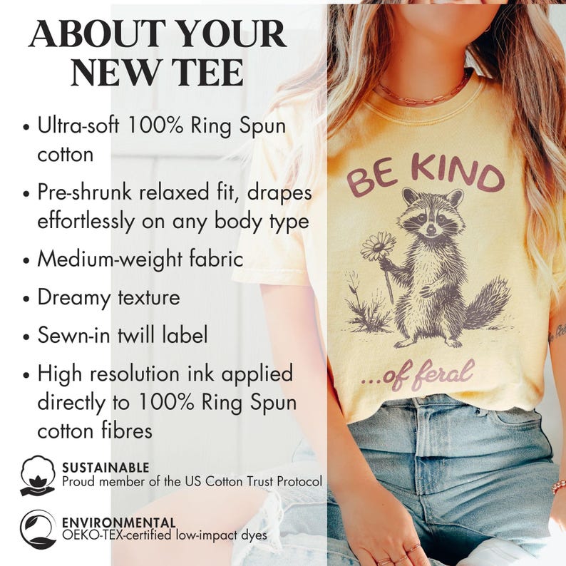 May include: A yellow t-shirt with a raccoon graphic and the text "Be Kind...of feral". The shirt is made of 100% ring spun cotton and is pre-shrunk for a relaxed fit. The shirt is also sustainably made with low-impact dyes.
