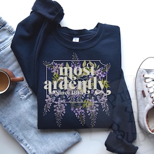 Op de afbeelding: Een marineblauw sweatshirt met een bloemenontwerp en de tekst "most ardently since 1814".