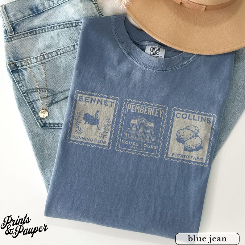 K&ouml;nnte beinhalten: Ein blaues Comfort Colors T-Shirt mit drei Briefmarken-Designs. Die Briefmarken lauten "Bennett Running Club", "Pemberley House Tours Est. 1813" und "Collins Potato Farm". Das Shirt wird mit hellblauen Jeans und einem beigen Hut kombiniert.