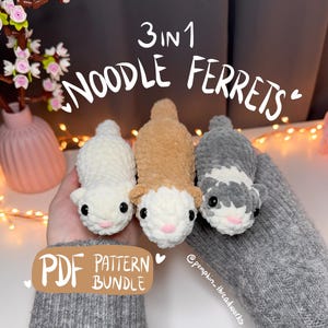 Puede incluir: Tres peluches de hurón de ganchillo en blanco, marrón y gris, cada uno con ojos negros y narices rosas. La imagen incluye el texto "3 en 1 NOODLE FERRETS" y "PDF PATTERN BUNDLE". Los peluches se sostienen en una manga gris.
