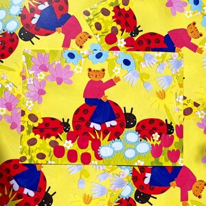May include: A whimsical illustration featuring a tiger-like character in a pink shirt and blue pants, seated on a large red ladybug with black spots. The background is a vibrant yellow with flowers and more ladybugs.
