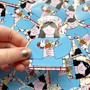 Peut inclure: Un autocollant bleu avec un personnage de dessin animé tenant une variété de petits jouets. Le personnage porte un pull bleu et a les cheveux noirs. L'autocollant a un fond à carreaux et le texte "J'aime les bibelots" au-dessus du personnage.