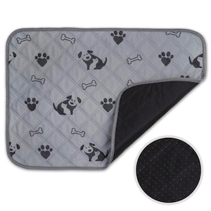 May include: A rectangular pet bed with a light grey quilted top featuring a repeating pattern of black paw prints, dog illustrations, and bones. The bed has a dark grey border and a black, textured underside. A circular inset shows the underside texture.