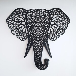 Puede incluir: Corte de papel negro de la cabeza de un elefante con intrincados patrones de mandala en todo el diseño.
