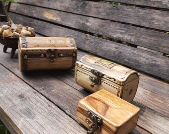 May include: Three wooden boxes with brass hinges and latches. The boxes are different sizes and are arranged on a wooden surface.