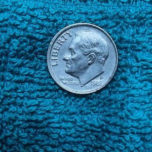 May include: A silver-coloured United States ten-cent coin, known as a dime, featuring the profile of Franklin D. Roosevelt facing left. The coin is inscribed with the word LIBERTY, the phrase IN GOD WE TRUST, the year 1988, and the mint mark P.