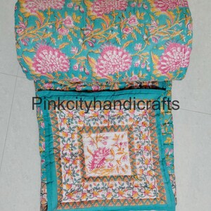 Puede incluir: Una colcha de algod&oacute;n azul turquesa con estampado floral. La colcha est&aacute; doblada por la mitad y el estampado floral es visible en ambos lados. La colcha est&aacute; cosida a mano y tiene un dise&ntilde;o tradicional indio.
