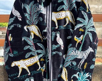 Könnte beinhalten: Schwarze Jacke mit Reißverschluss und Dschungel-Muster. Das Design zeigt Leoparden, Zebras, Vögel und tropische Pflanzen in Weiß und Gelb. Die Jacke hat ein gestreiftes Futter und einen Kragen.