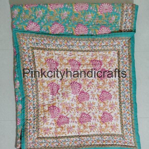 Puede incluir: Una colcha de color azul turquesa y blanco con estampado floral, con una colcha interior m&aacute;s peque&ntilde;a con estampado floral rosa y blanco. La colcha tiene un borde decorativo con un patr&oacute;n repetitivo de tri&aacute;ngulos. El texto "Pinkcityhandicrafts" es visible en el centro de la colcha.