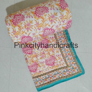 Op de afbeelding: Een wit katoenen dekbed met een bloemenprint in roze en gele tinten. Het dekbed heeft een turquoise rand met een geometrisch patroon. Het dekbed is opgerold en de tekst "Pinkcityhandicrafts" is zichtbaar.