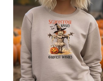May include: A beige sweatshirt with a graphic of a scarecrow holding a pumpkin and the text "Scarecrow Kisses Harvest Wishes".