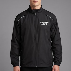 May include: A black full-zip windbreaker jacket featuring a high collar, long sleeves with elastic cuffs, and white piping details along the shoulders. The text CUSTOM LOGO is printed in white on the upper left chest area of the garment.