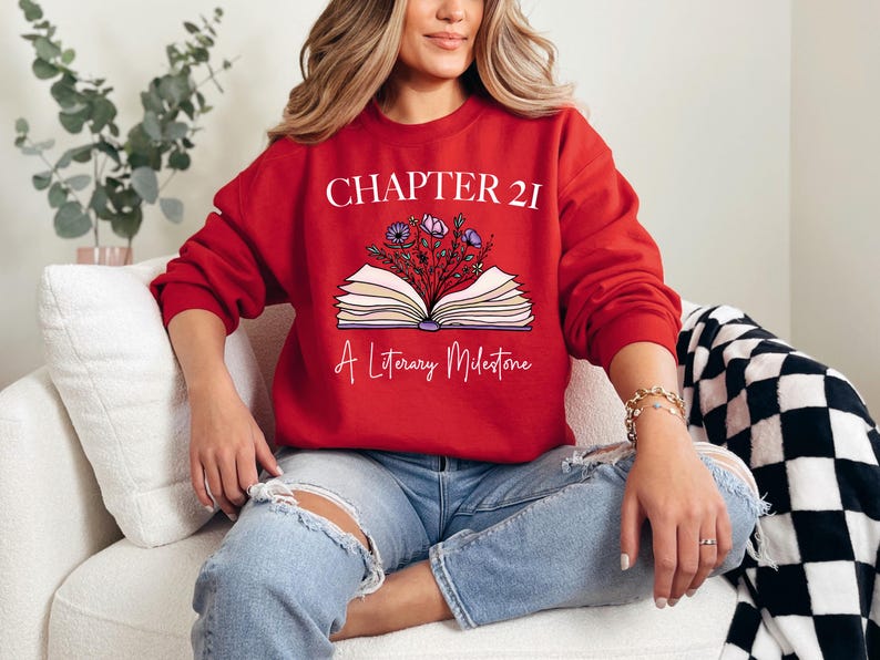 a woman sitting on a couch wearing a red sweatshirt