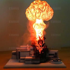 Puede incluir: Modelo impreso en 3D de una explosión nuclear, con una nube en forma de hongo y una base detallada. El modelo está iluminado con un brillo naranja, simulando el calor y la luz de una explosión atómica. La base es blanca con detalles negros.