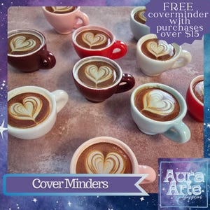 May include: A collection of miniature coffee cup magnets, each featuring a heart-shaped latte art design. The cups come in various colors including red, white, pink, and light blue. Text on the image reads: FREE coverminder with purchases over $15.